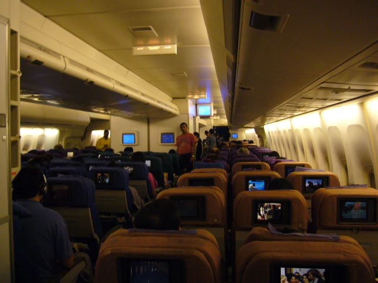 people standing on seats in an airplane watching tv
