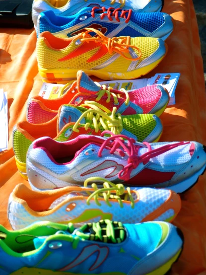 a row of bright shoes sitting on top of an orange table