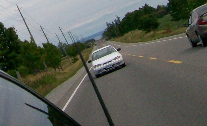 the rear view mirror of a car is reflecting a parked white car