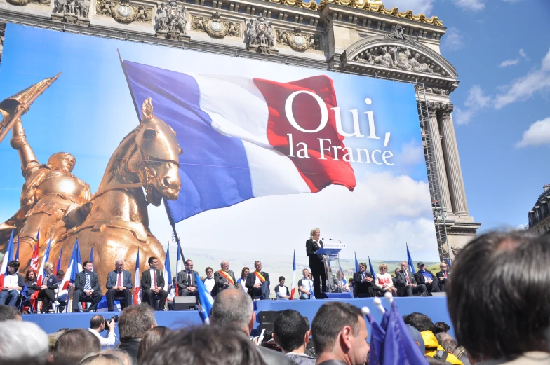 a crowd in front of a large advertit showing men in military uniform