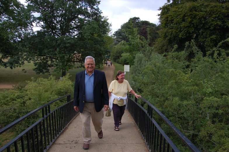 a man and woman walk across a bridge over some water