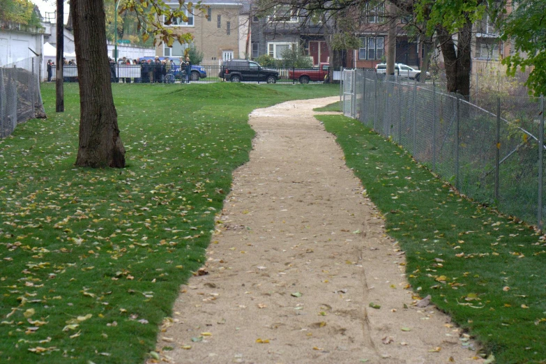 the sidewalk is lined by a fenced yard