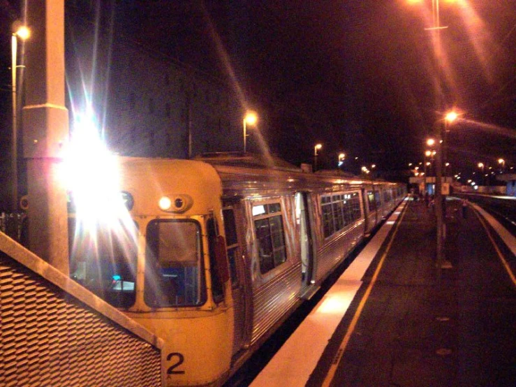 the passenger train is at the platform in the night