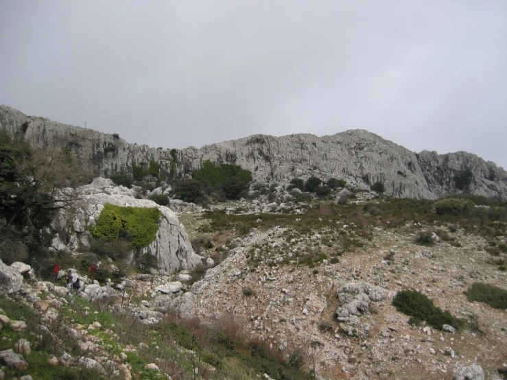 group of people hiking up an mountain with rocky terrain