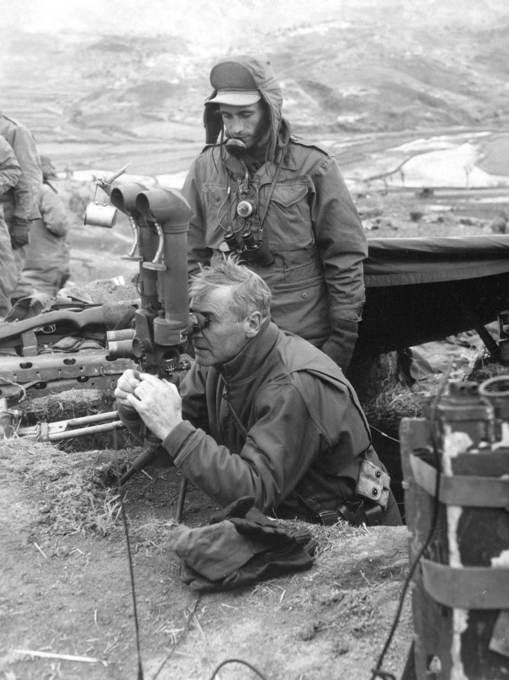 two soldiers looking at the ground with their equipment