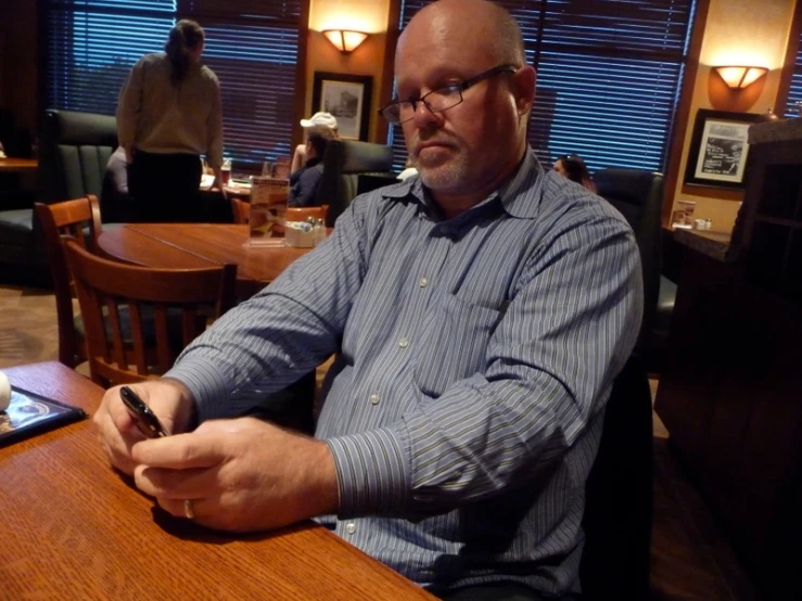a man is at a table holding a cellphone