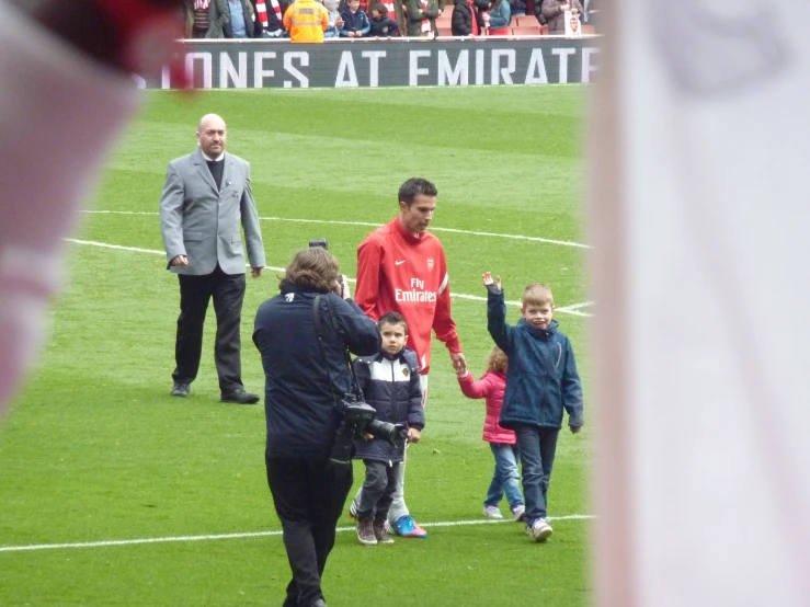 a  and two men walking with one boy along a soccer field