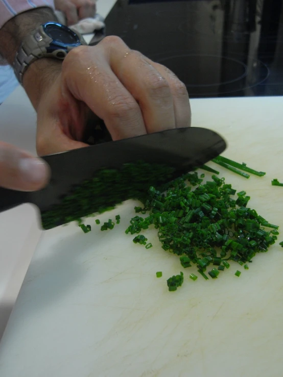someone is slicing up green vegetables with a chef's knife