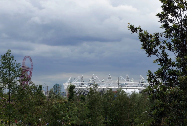 a view of a stadium through trees to some buildings