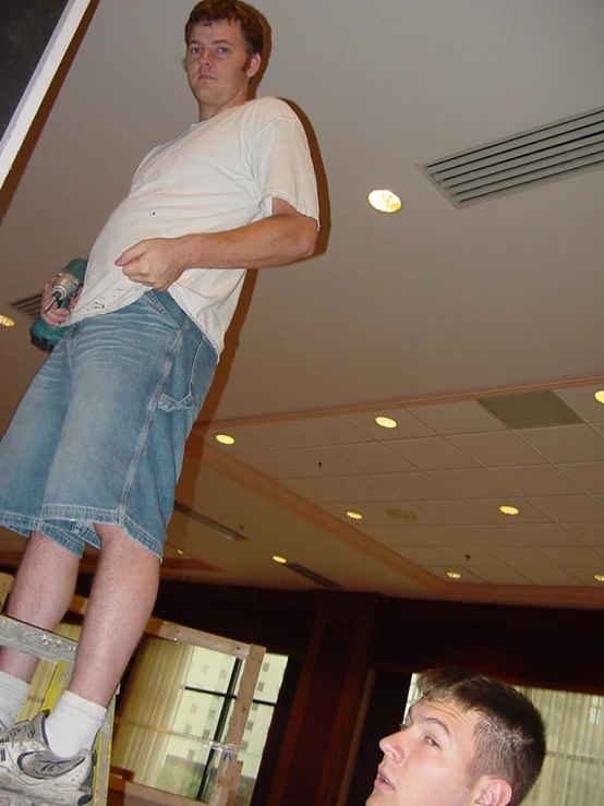 two men standing in a room with two other men holding remote controls