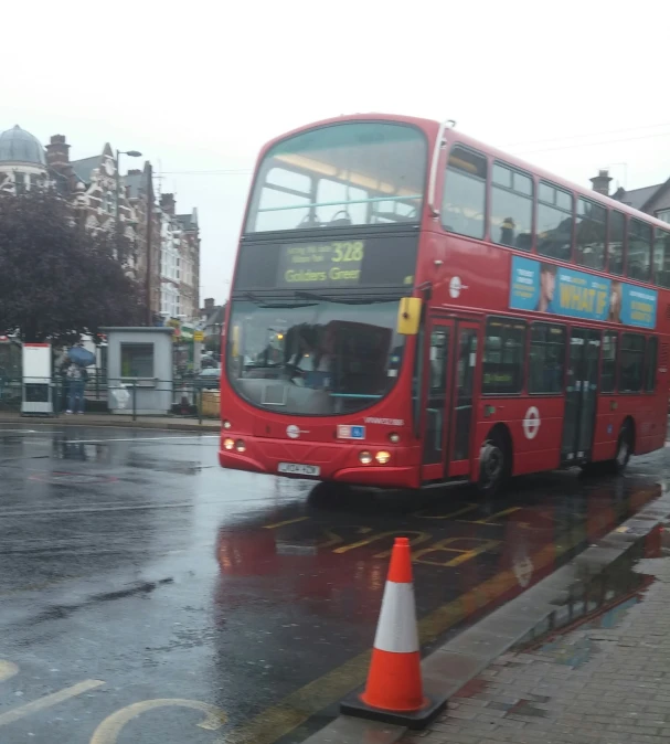 a red bus driving through an orange cone