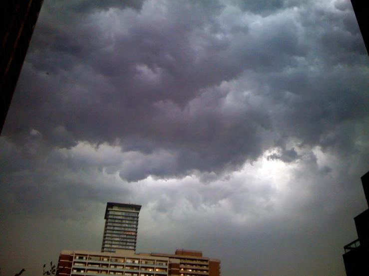 a tall building sits under a very cloudy sky