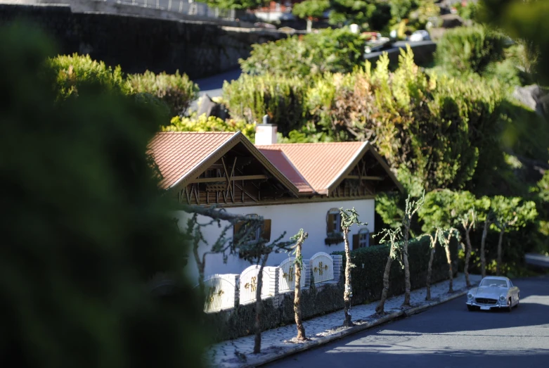 a house sitting on the side of a street near a white car