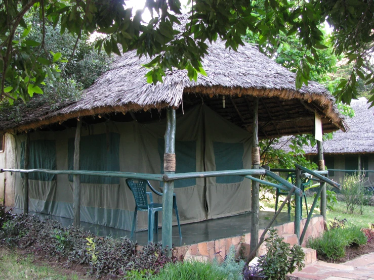 an old thatched hut with trees and bushes surrounding it