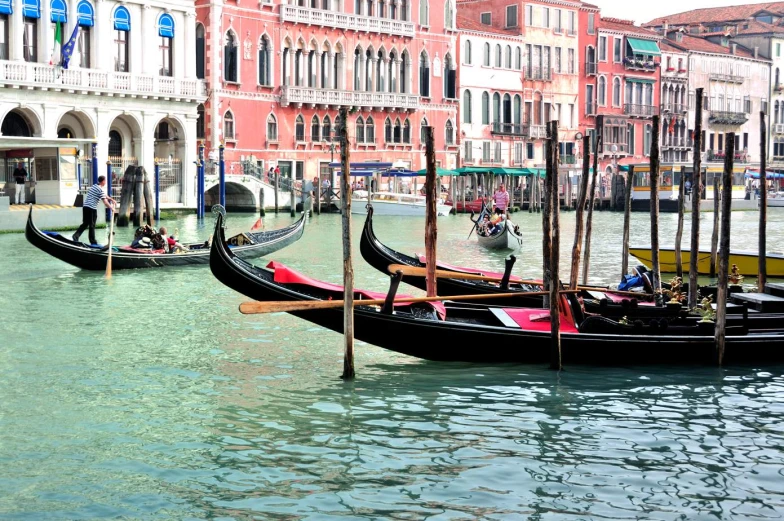 three gondolas sit in the water near buildings on a street