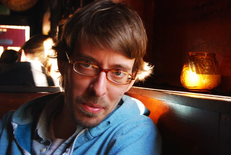 a man with glasses sitting in a booth