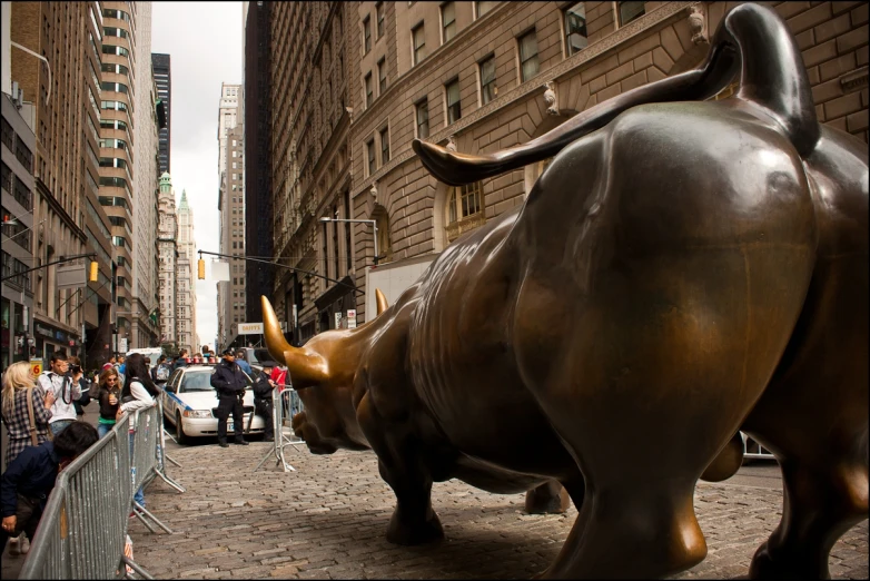 a bull statue on the sidewalk is facing away