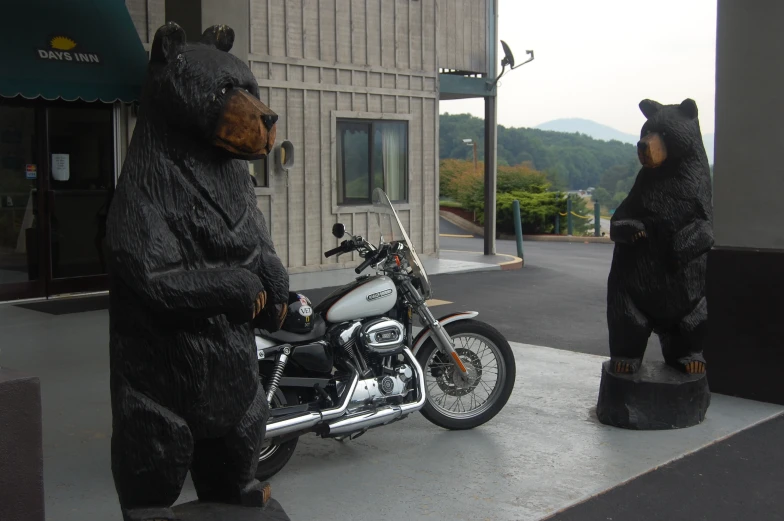 there is a motorcycle parked next to a large bear statue