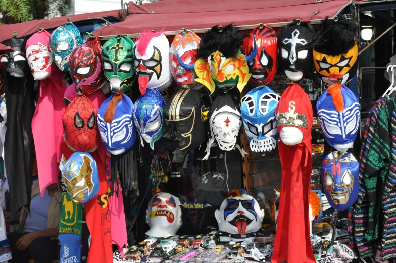 colorful masks are hanging on a wall outside