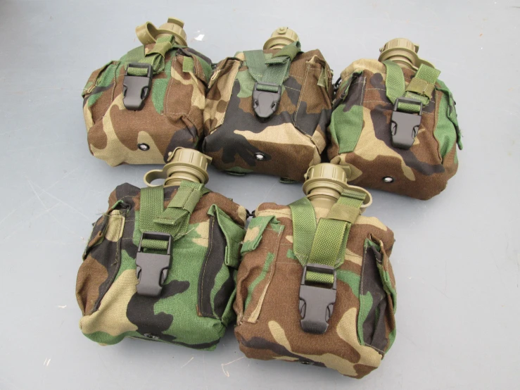 four camouflage waist bags sitting on a gray surface
