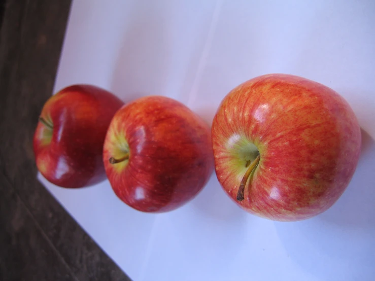 three apples are sitting on a paper and one is not