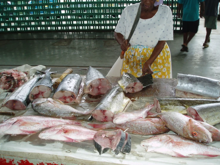 a woman in white is at a market stall with fish