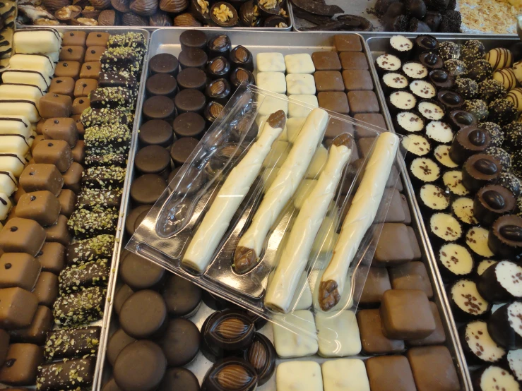 chocolate, vanilla, and other sweets sitting on trays in a bakery