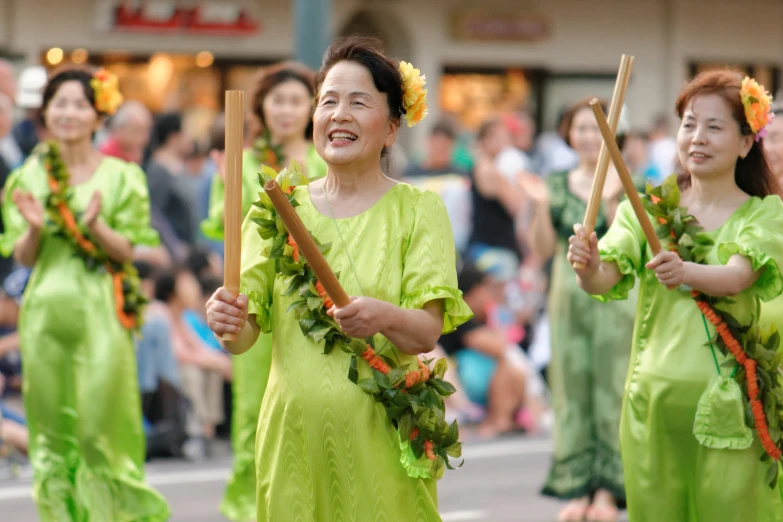 three women dancing with some bamboo poles