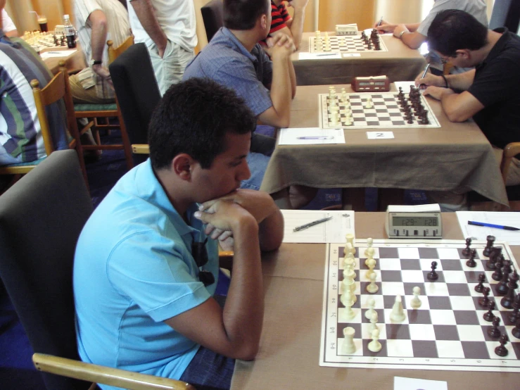 several people sitting at tables playing chess