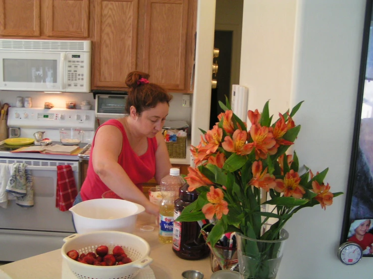 a lady putting ingredients in a bowl next to some flowers