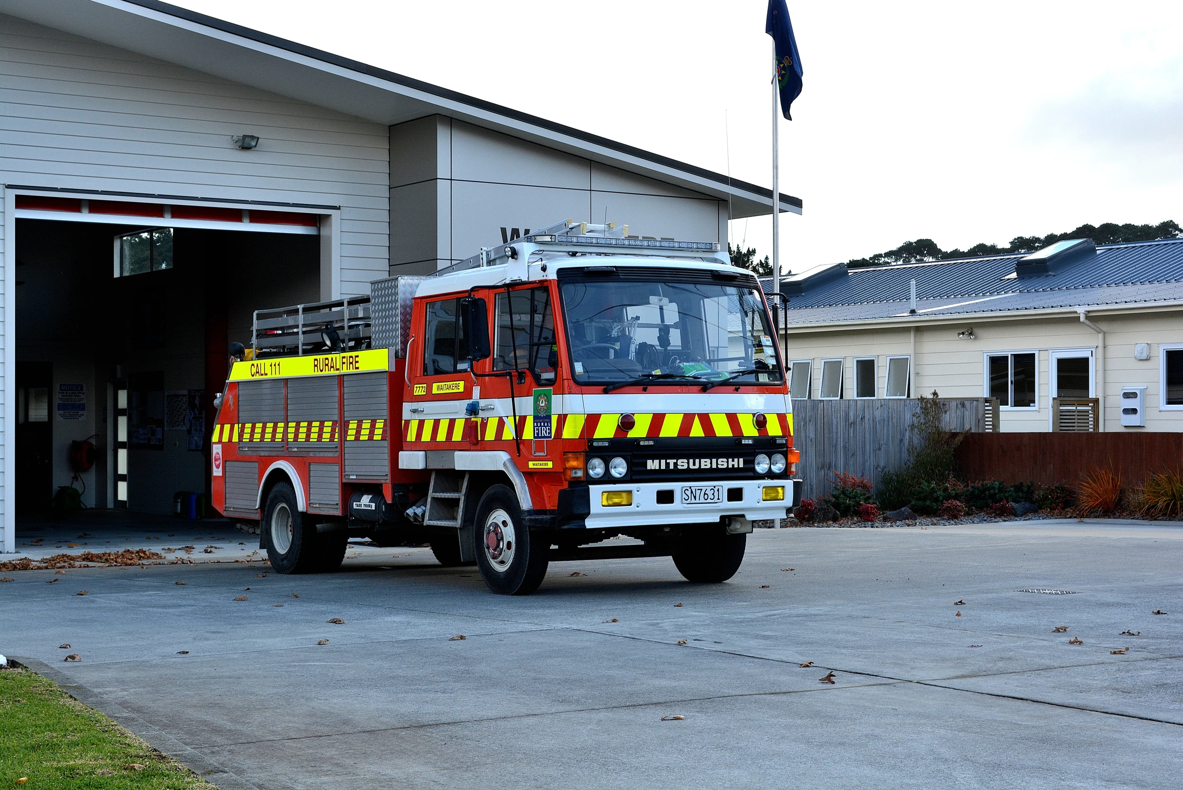 a red and yellow tow truck is in the driveway