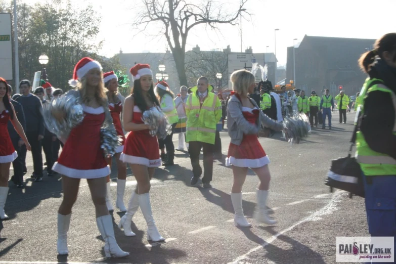 a group of women in santa hats and dress dancing down the street