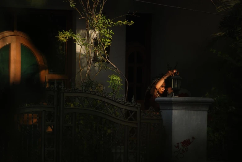 a woman is sitting by a gate in the dark