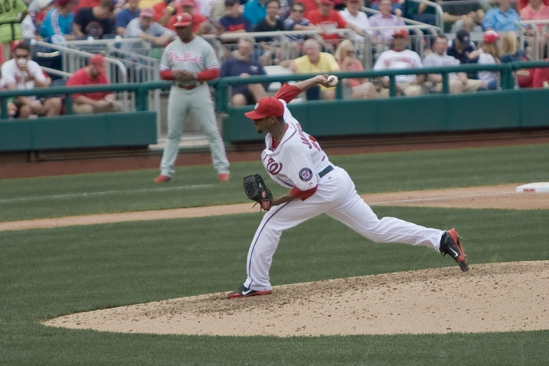 a pitcher in uniform winding up to pitch the ball during a game