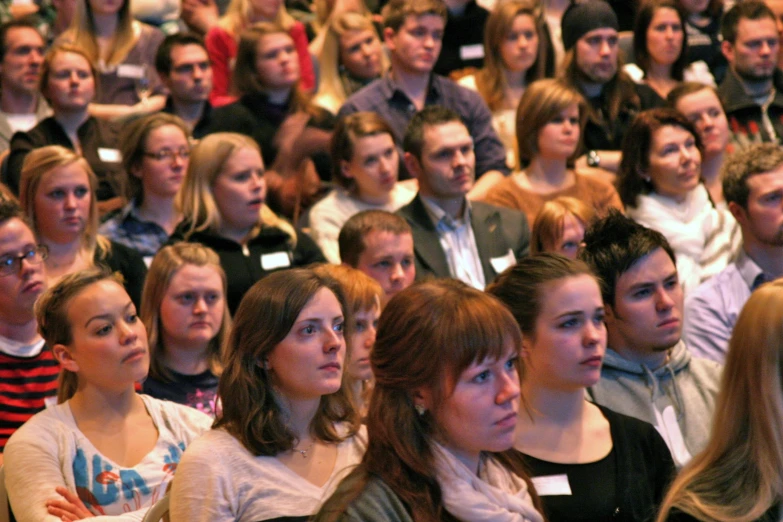 the people are sitting in the large audience