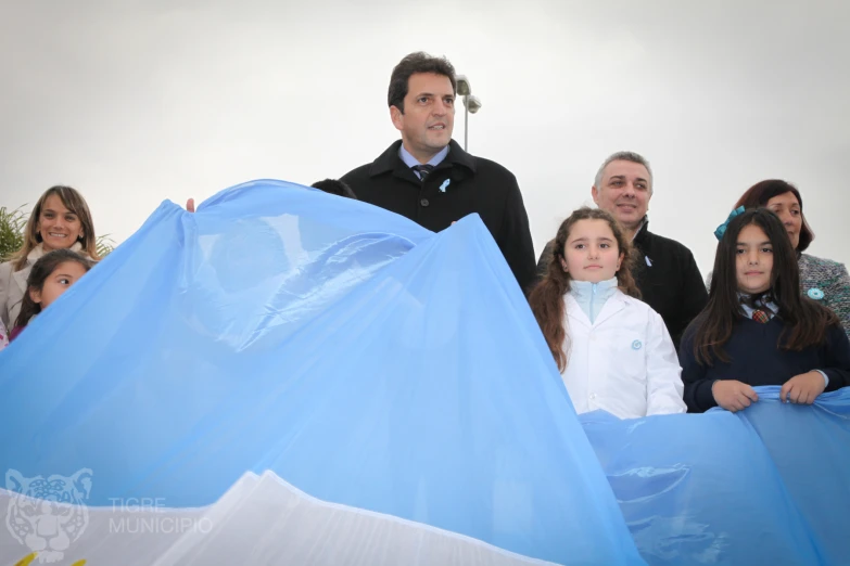 a family in formal wear posing for a po while holding a giant blue tarp