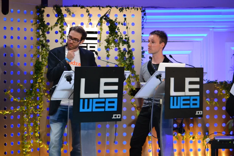 two men standing at podiums making a speech