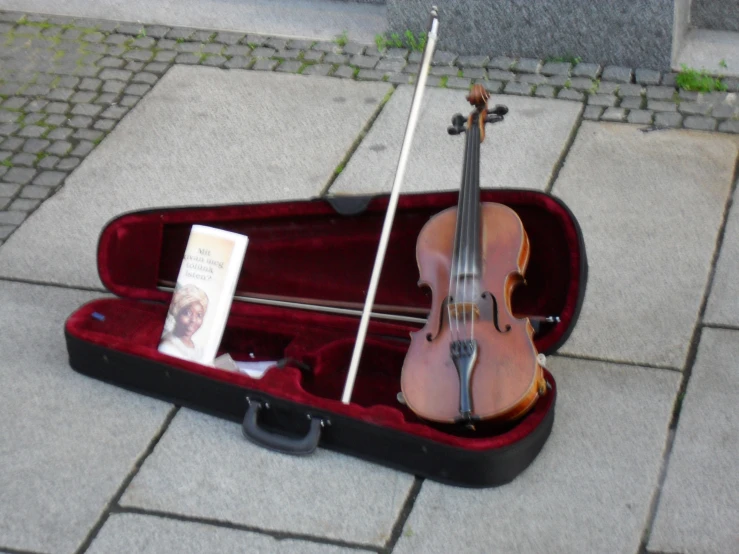 a violin lying in a case on the sidewalk