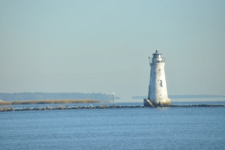 a lighthouse on an ocean with a hazy sky