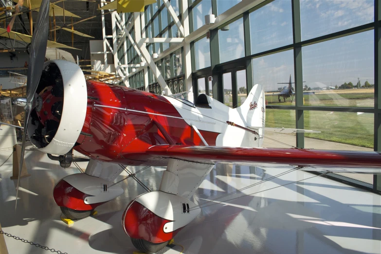 a red and white plane is parked inside of a large building