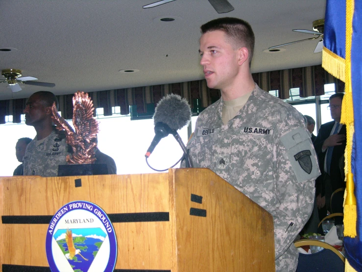 a man in military fatigues standing at a podium with a microphone