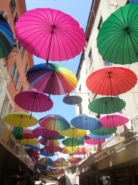 many colorful umbrellas hanging over a small street