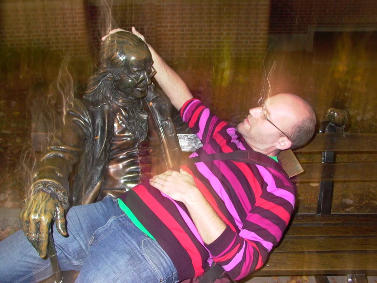 a man touching a statue on top of a bench