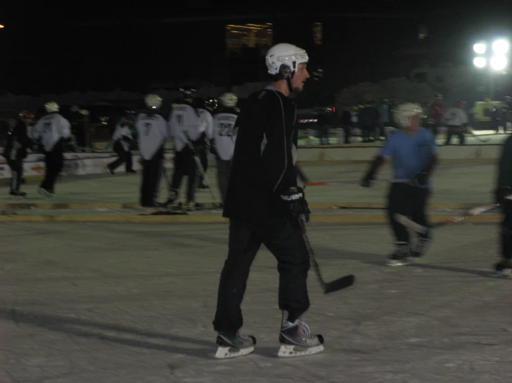 several skateboarders are riding on an asphalt ground at night