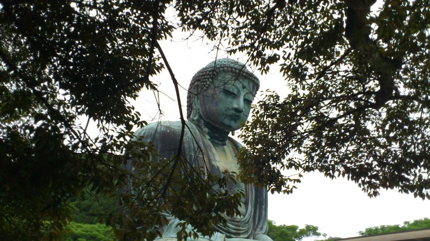 a big statue sits among some trees outside