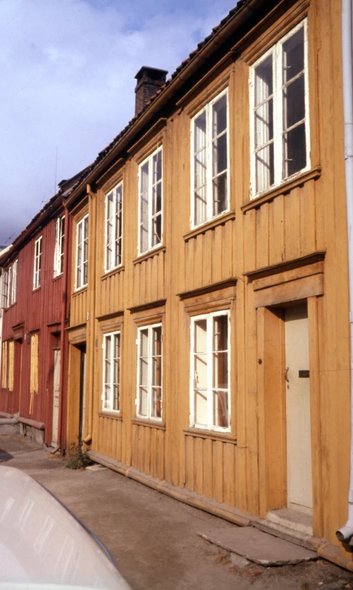 the front of a wooden house with windows, a car and red wood siding