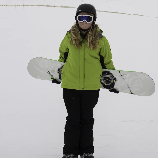 a person holding a snow board standing in the snow