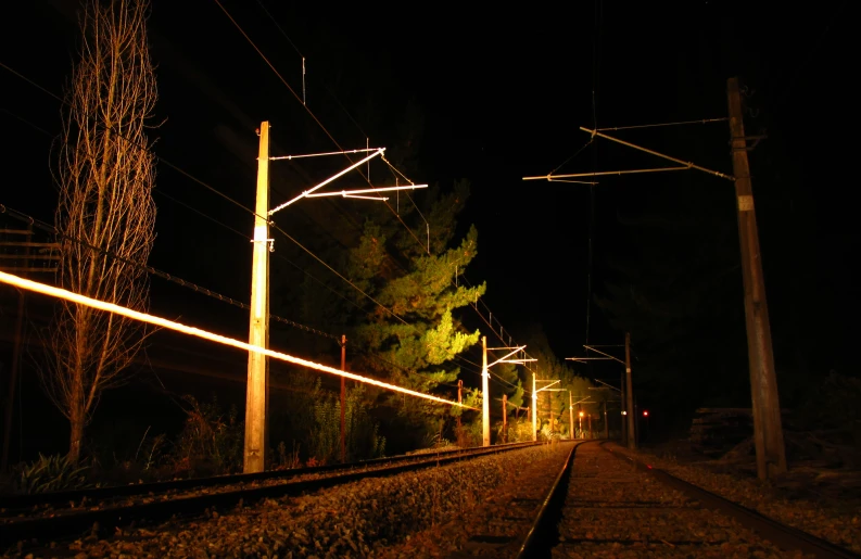 a train track at night with a line lit up along the tracks