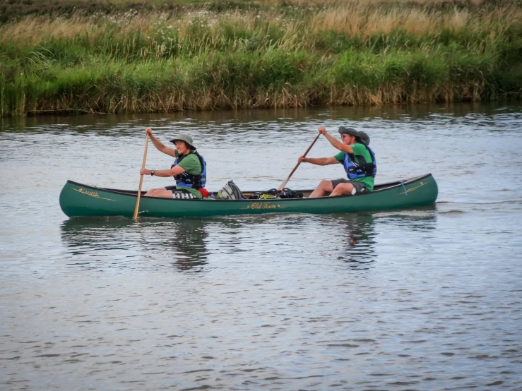 two people in green paddle canoes on the water