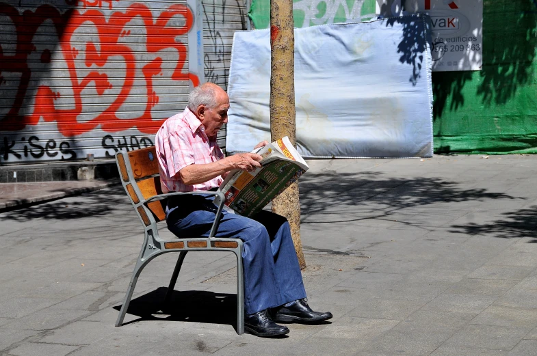 an older man is reading a book on the street